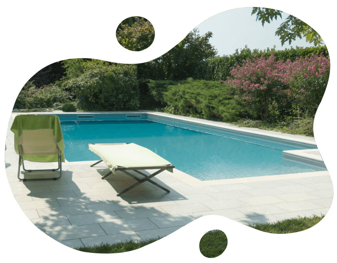 Big Rectangular Swimming Pool with Pavement in large White Tiles Enclosed by Trees and Bushes